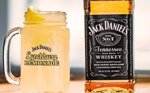 En iskallad Jack Daniel's Lynchburg Lemonade i ett glas med handtag, bredvid en flaska Jack Daniel's Tennessee Whiskey.