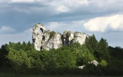 Imponujący okiennik wielki, skalna brama wśród zieleni, z ukrytą chatką.