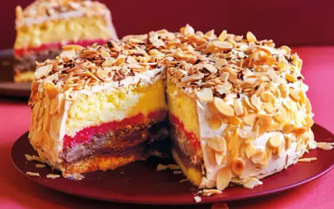 Una fetta di pizza dolce abruzzese, stratificata con crema, cioccolato e confettura, ricoperta di mandorle tostate e scaglie di cioccolato.