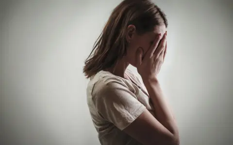 Kobieta zakrywa twarz dłońmi, co może symbolizować różne psychozy objawy, takie jak przytłoczenie czy izolacja.