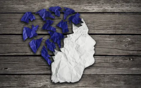 Zgnieciona papierowa głowa, której fragmenty odlatują, symbolizuje problem z pamięcią krótkotrwałą.