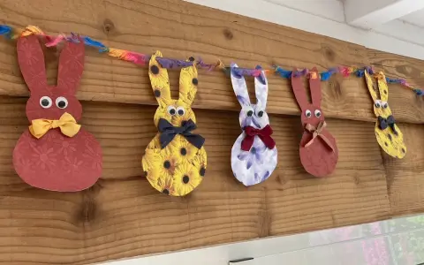 Guirlande de lapins colorés, déco de Pâques à faire soi-même avec récup. Des lapins en papier aux motifs variés, ornés de nœuds et d'yeux mobiles, suspendus à une ficelle multicolore.