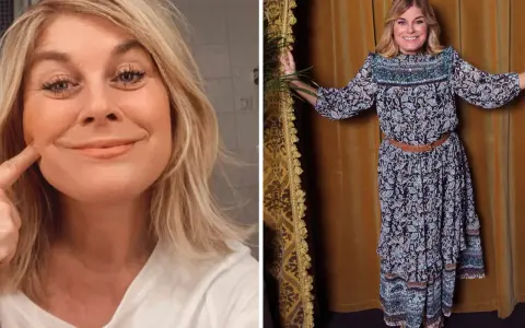 Pernilla Wahlgren ler och pekar på sitt ansikte. Hon bär en mönstrad klänning och ser glad ut.