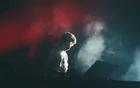 Un DJ dans la fumée rouge et blanche, plongé dans sa musique. Combien de temps avant le traumatisme sonore ?