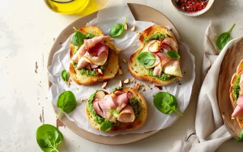 Pyszne kanapki z chrupiącą grzanką, aromatycznym pesto na kanapki, wędliną i świeżą bazylią.