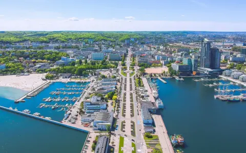 Widok na Gdynię z lotu ptaka: port jachtowy, plaża, nowoczesne budynki i zieleń. Ciekawe ciekawostki o Gdyni czekają na odkrycie!