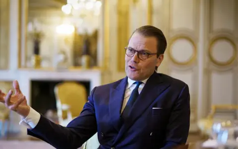 Prins Daniel i mörk kostym, med glasögon, gestikulerar. Rykten om prins Daniel otrogen sprids.