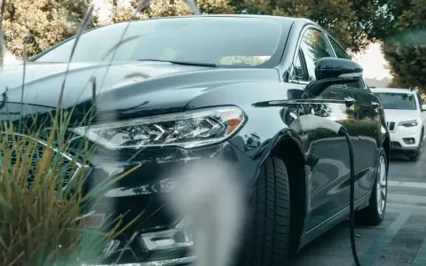 Ciemna toyota hybryda podłączona do ładowarki, gotowa na ekologiczną podróż.