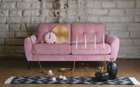 En dyr soffa i sammet, rosa, med dekorativa föremål som en golfklubba, bollar, ljusstakar och ananasskulpturer.