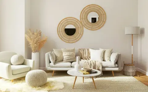 Przytulny salon w stylu scandi chic: jasna sofa, fotel, okrągłe lustra z plecionki, dywan i dekoracje z trawy pampasowej.