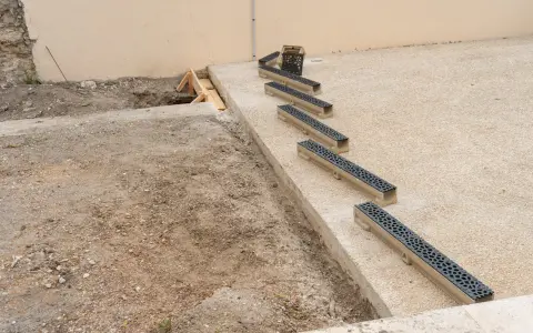 Installation de plusieurs éléments de pose caniveau sur un chantier.