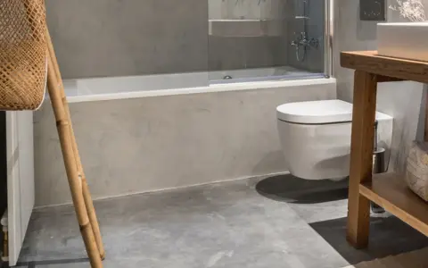 Baño moderno con ducha y WC suspendido. El suelo de microcemento y paredes grises dan un toque minimalista. Ideal para calcular el precio reforma baño 4 m2.