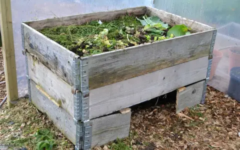 En kompost av pallkragar fylld med trädgårdsavfall. Enkel och effektiv lösning för att bygga kompost.