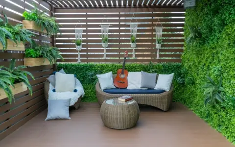 Terraza acogedora con muebles de mimbre, plantas colgantes y una pared verde. Ideal para relajarse, como cubrir una terraza con poco dinero.