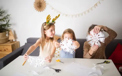 Dzieci uczą się, jak narysować śnieżynkę, wycinając papierowe ozdoby.