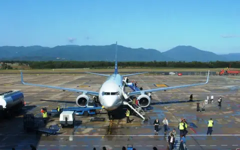 Flugzeug am **Girona Flughafen** mit Passagieren, die einsteigen. Berge im Hintergrund.