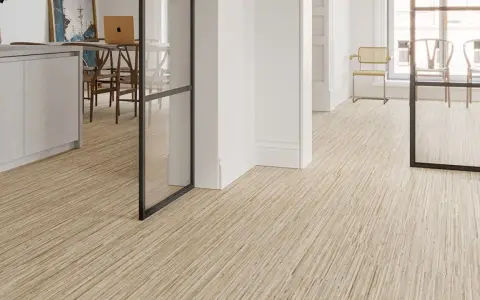 Un moderno revestimiento del suelo de madera clara con un diseño lineal crea un ambiente acogedor en un interior luminoso.