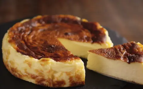 Tarta de queso al horno casera, dorada y cremosa, con una porción lista para disfrutar.