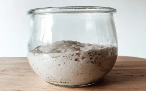 Aktiver Sauerteig im Glas, bereit für ein Lievito Madre Rezept. Blasen zeigen die Gärung.