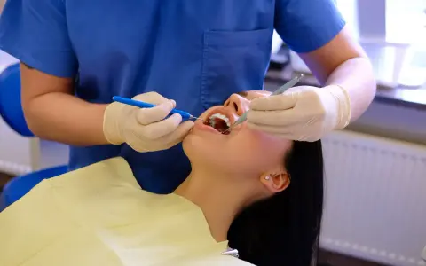 Dentysta wykonuje fluoryzację zębów pacjentki, dbając o ich zdrowie i ochronę przed próchnicą.