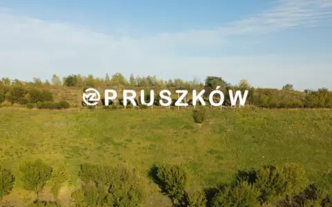 Napis "Pruszków" na tle zielonego wzgórza. Zastanawiasz się nad cenami mieszkań Pruszków?
