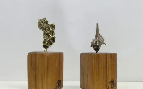 Deux sculptures en bronze, l'une abstraite, l'autre en forme de coquillage, sur des socles en bois portant la signature des fondeurs de bronze.