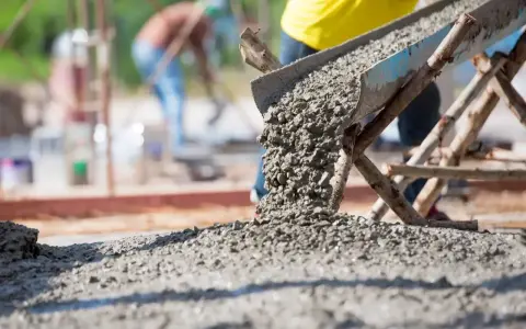 Betoniarka wylewa świeży beton. Zastanawiasz się, ile cementu na kubik betonu? Budowa trwa.