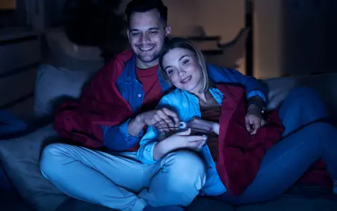 Para spędza miły wieczór, otulona kocem, oglądając lekkie filmy na wieczór i jedząc popcorn.