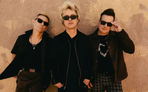 Green Day Sverige: Billie Joe Armstrong, Mike Dirnt och Tré Cool poserar framför en vägg.