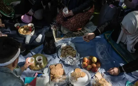 Familie feiert Fastenbrechen im Islam mit Picknick im Freien. Kekse, Früchte und Kaffee werden geteilt.