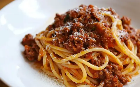 Pyszne spaghetti bolognese z bogatym sosem mięsnym i startym parmezanem na białym talerzu.