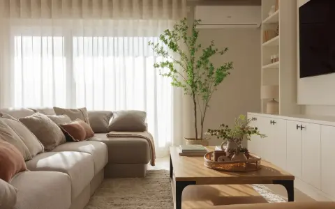 Acogedora distribución salón con sofá modular, mesa de centro de madera, alfombra mullida y planta decorativa.