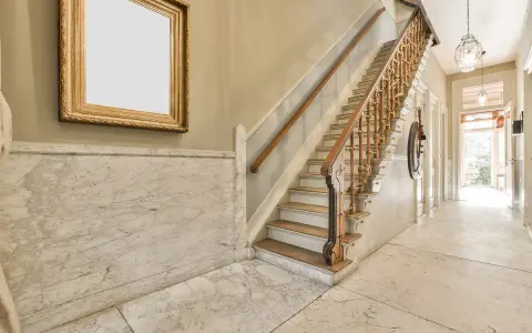 Elegante rellano de escalera comunitaria con mármol y un cuadro dorado. Ideas para decorar rellano escalera comunidad.