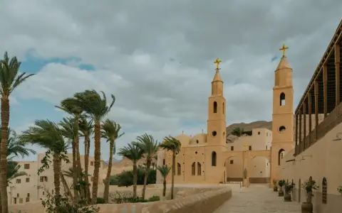 A monastery courtyard with palm trees and a bell tower, evoking the spirit of the desert fathers and mothers.