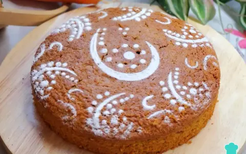 Bizcocho de zanahoria decorado con azúcar glas en un diseño de lunas y puntos. Se ve delicioso y esponjoso.