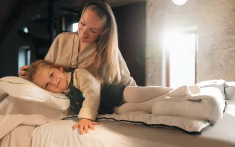 Mutter streichelt Kind, das auf einem Kissen liegt. Gute Nacht-Tipps für Kinder 11 Jahre.