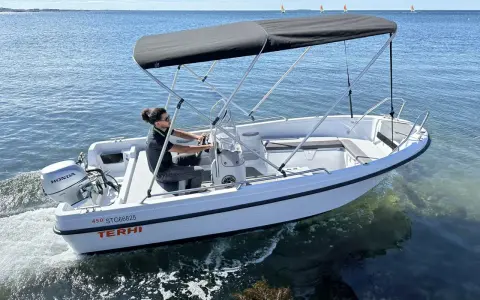 Ce bateau Terhi 450, propulsé par un moteur Honda de 6 cv, navigue sur une mer calme. Idéal pour explorer les côtes.