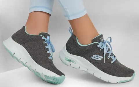 Graue Skechers-Sneaker mit hellblauen Schnürsenkeln und mintgrünen Akzenten. Die Sohlen zeigen die Skechers Sohlen Unterschiede, mit einer markanten ArchFit-Technologie.