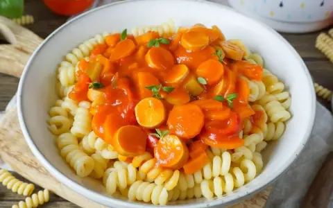 Herzhaftes Wurstgulasch Rezept mit Fusilli-Nudeln, Karotten und Paprika in Tomatensauce, garniert mit frischen Kräutern.