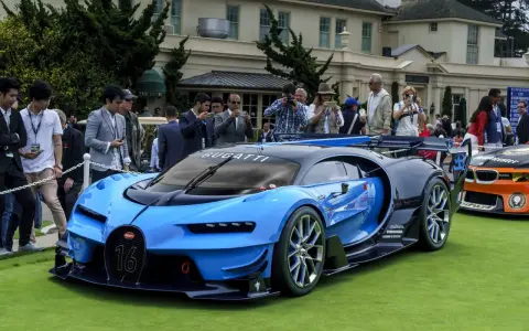 Niebieski Bugatti Veyron z numerem 16 na masce, otoczony tłumem ludzi robiących zdjęcia, na tle eleganckiego budynku.