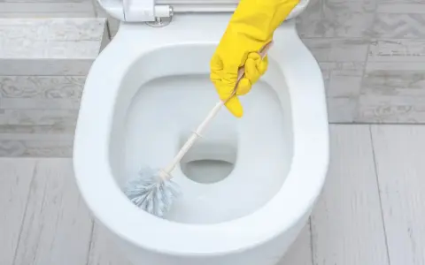 Main jaune pour nettoyer les toilettes.