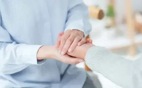 Dłonie trzymające się nawzajem, symbol wsparcia i troski.