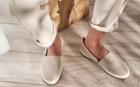 Un uomo indossa espadrillas in tela beige con pantaloni chiari arrotolati. Perfette per un look casual estivo, scopri come abbinarle.