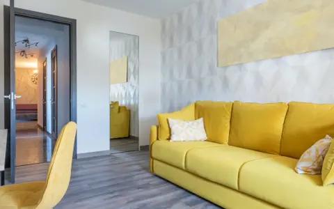 Un sofá amarillo vibrante y un sillón a juego llenan la habitación, destacando los alegres colores de sofás.