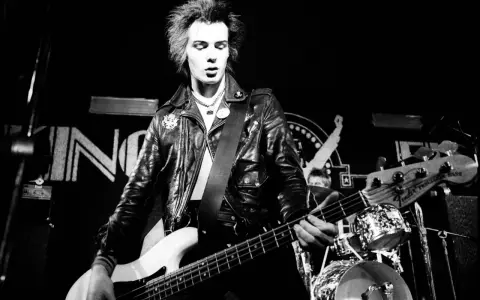 Sid Vicious, Punk-Ikone, spielt Bass auf der Bühne. Seine wilden Haare und Lederjacke unterstreichen seine rebellische Ausstrahlung. Seine Musik erfüllt die "sid wishes" des Publikums.
