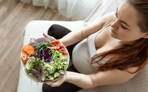 Kobieta w ciąży delektuje się zdrową sałatką, dbając o dietę w ciąży. Kolorowe warzywa to podstawa.