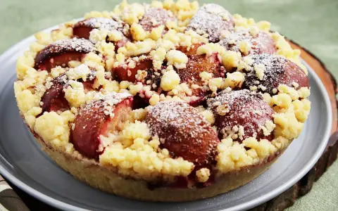 Ein köstlicher pflaumenkuchen ohne hefeteig, bestreut mit Puderzucker und knusprigen Streuseln.