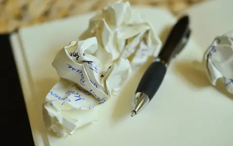 Zgniecione kartki z notatkami i długopis. Ilustruje, jakie są najczęstsze błędy w adresowaniu zaproszeń do par niebędących w małżeństwie.