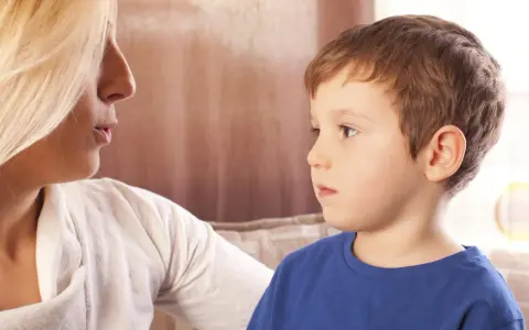 Kobieta rozmawia z chłopcem, który ma afazję mowy. Skupienie na twarzach i próbie komunikacji.