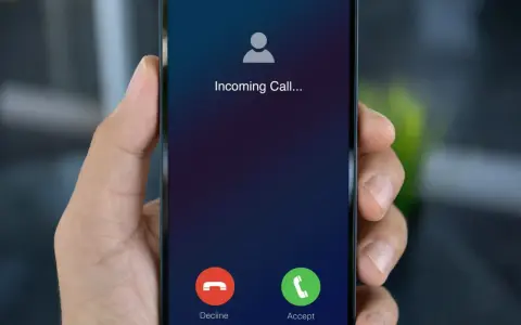 Dłoń trzyma smartfon z ekranem "Incoming Call...". Czy to połączenie z zagranicy, gdy działa co to roaming?